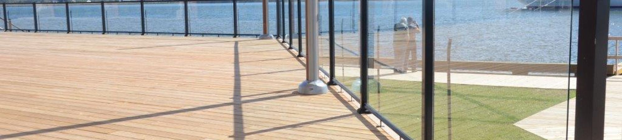 Large outdoor deck space with surface mount glass railings and black aluminum top and bottom rails